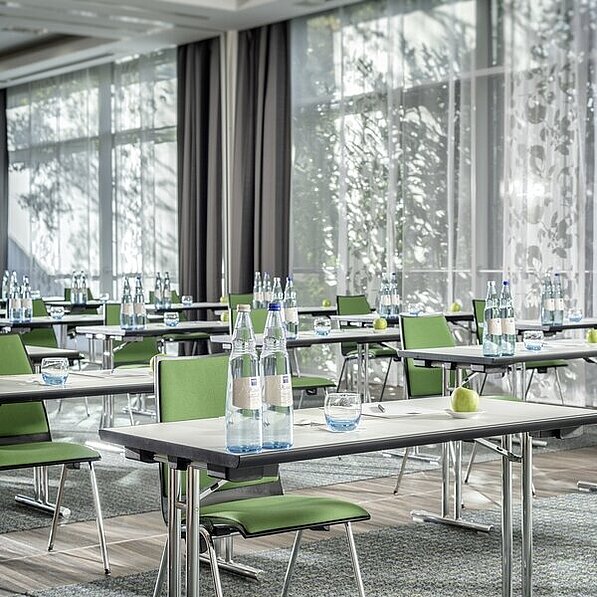 Tagungsraum im Hotel in Neuss mit Einzeltischen und grünen Stühlen 