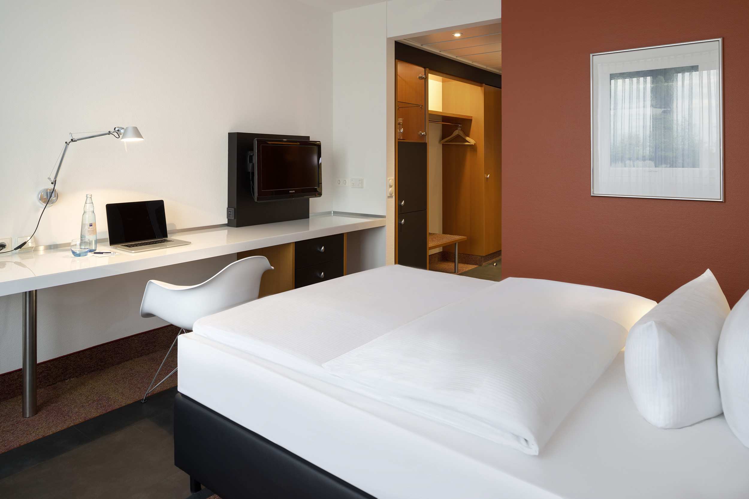 Standard Einzelzimmer im Hotel in Neuss mit roter Wand und Schreibtisch 